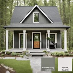 a small gray house with white trim and black shutters on the front door is surrounded by trees