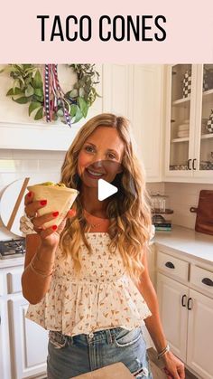 a woman standing in a kitchen holding up a plate with food on it and the words taco cones above her head