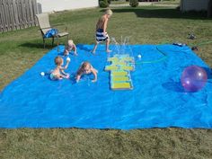 children playing in an inflatable pool on the lawn with water sprinkles