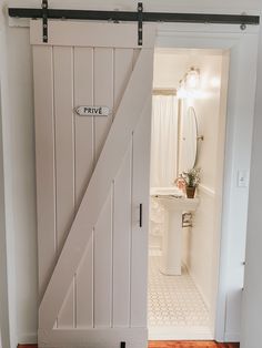 an open door leading to a bathroom with a sink and toilet in the background,