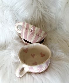 two ceramic cups sitting next to each other on a white fur covered surface with the words happy mother written on them