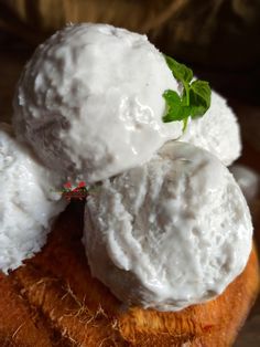 three scoops of ice cream sitting on top of a piece of bread with a sprig of green leaf