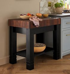 a wooden table with bowls and plates on it in front of a kitchen counter top