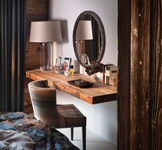 a bedroom with a mirror, desk and chair next to a lamp on the wall