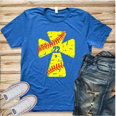 a blue t - shirt with yellow and red baseballs on it, next to jeans