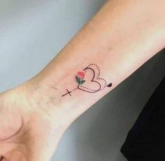 a woman's arm with a small cross and heart tattoo on the left wrist