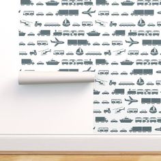 a white wall with a pattern of different types of vehicles on it and a roll of toilet paper in front of it