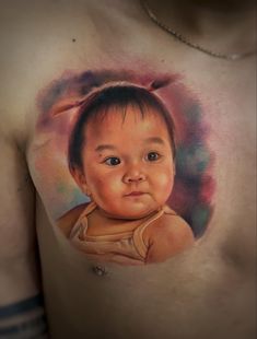 a man with a tattoo on his chest has an image of a baby's face