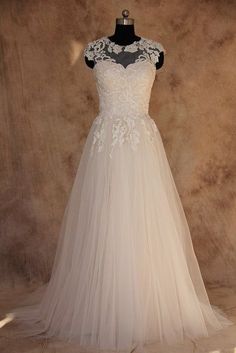 a white wedding dress on display in front of a wall