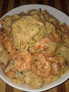 pasta with shrimp and mushrooms in a white bowl on a wooden table top, ready to be eaten