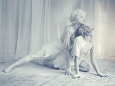 two women dressed in white pose for a photo