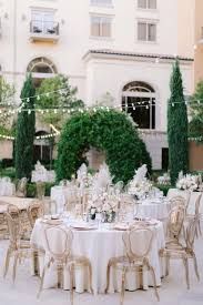 tables and chairs are set up in front of a large building with white linens on them