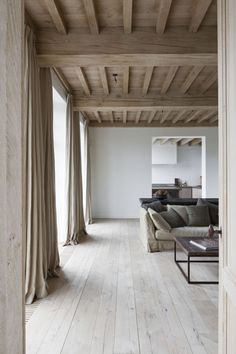 an open living room with wood floors and white walls, along with curtains on the windows