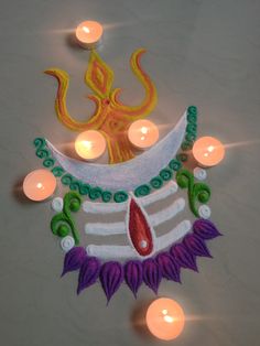 a decorated diya with lit candles in the background and an image of a demon on it