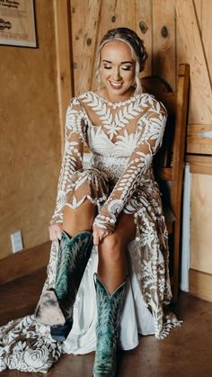 a woman sitting on top of a wooden chair wearing cowboy boots and a white dress