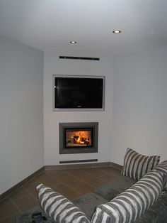 a living room filled with furniture and a flat screen tv mounted on the wall above an open fire place