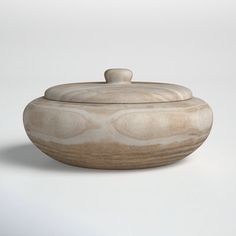 a bowl that is sitting on a white surface with a lid in the shape of an oval