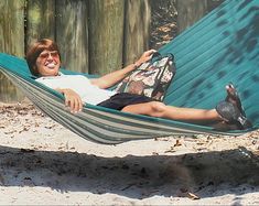 a woman laying in a hammock with her feet up on the ground and smiling