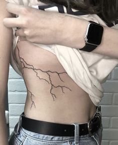 a woman's stomach with a lightning tattoo on her left side and an apple watch