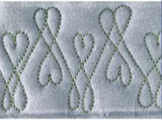 an embroidered design on the side of a piece of white fabric with green threadwork