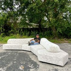 a man sitting on top of a couch in the middle of an empty parking lot