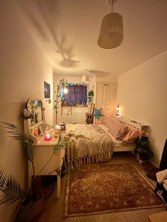 a bedroom with a bed, rug and plants on the floor in front of it