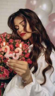 a woman holding flowers and candles in front of her face with the number 20 on it