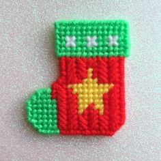 a crocheted christmas stocking ornament on a pink surface with green and red trim