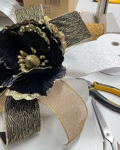 a black and gold flower sitting on top of a white table next to some scissors