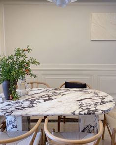 a marble table with chairs around it and a plant in the center on one side