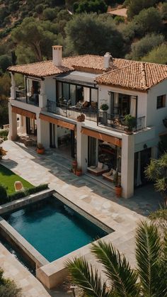 an aerial view of a house with a pool in the foreground and trees surrounding it