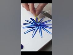 someone is cutting paper with scissors on a white board and blue star ornament