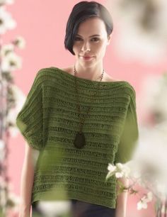 a woman wearing a green knitted top with buttons on the front and side, standing in front of a pink wall