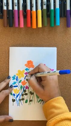 someone is drawing flowers on paper with crayons