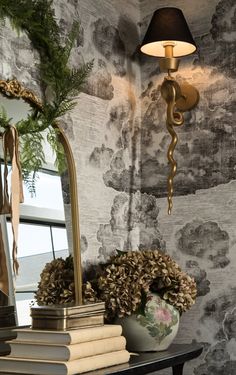 a table with books and a lamp on it in front of a wallpapered background