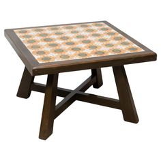 a small wooden table with an orange and green tile top on it's legs