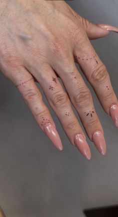 a woman's hand with pink nail polish and black dots on her nails is shown from the side