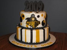 a three tiered cake decorated with black, yellow and white stripes on a wooden table