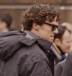 a woman with curly hair and sunglasses on her head is standing in front of other people