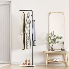 a coat rack with two coats hanging on it next to a mirror and wooden stool