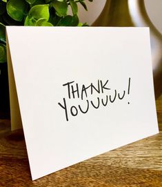 a thank you note sitting on top of a table next to a potted plant