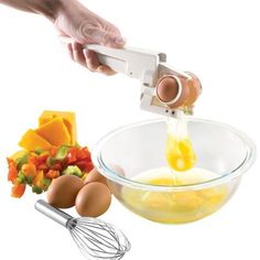 a hand holding a whisk over a bowl filled with eggs and other ingredients