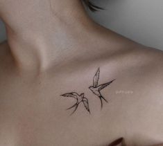 the back of a woman's shoulder with two birds flying above her chest tattoo