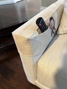 a remote control sitting in the pocket of a couch with sunglasses on it's back