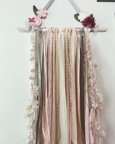 a wall hanging with ribbons and flowers on it's side, in the shape of a heart