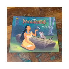 the book pocahontas is sitting on top of a wooden table next to a mouse