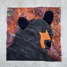 a patchwork bear with an orange star on it's head and black ears