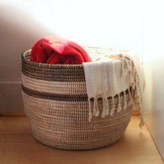 a woven basket sitting on top of a wooden floor next to a window sill