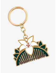 a gold keychain with a white flower and green leaves on the bottom part