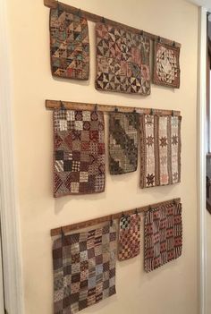 several quilts are hung on the wall in front of a stair case with wooden handrails